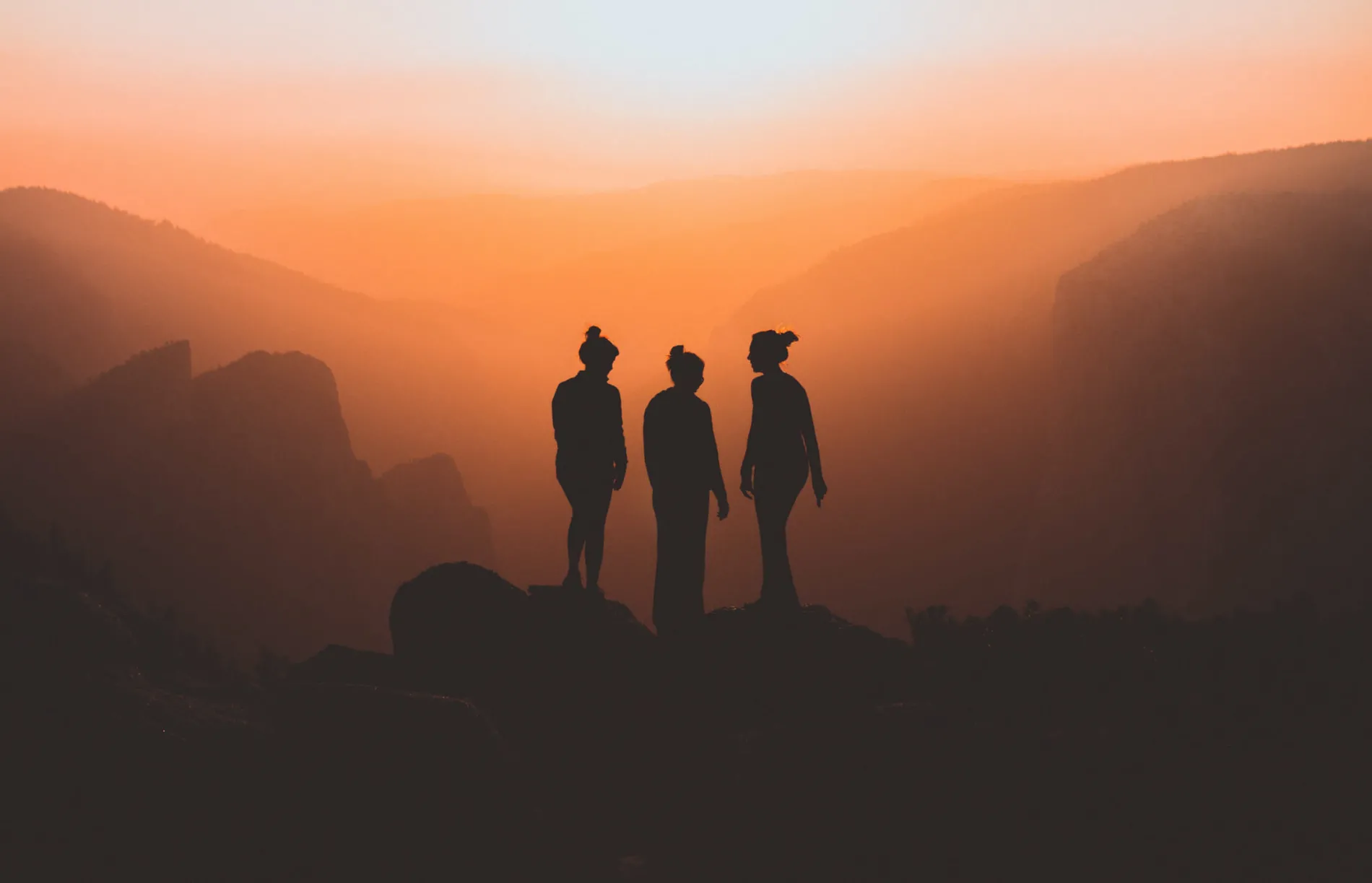 3 people on top of a mountain at sunset
